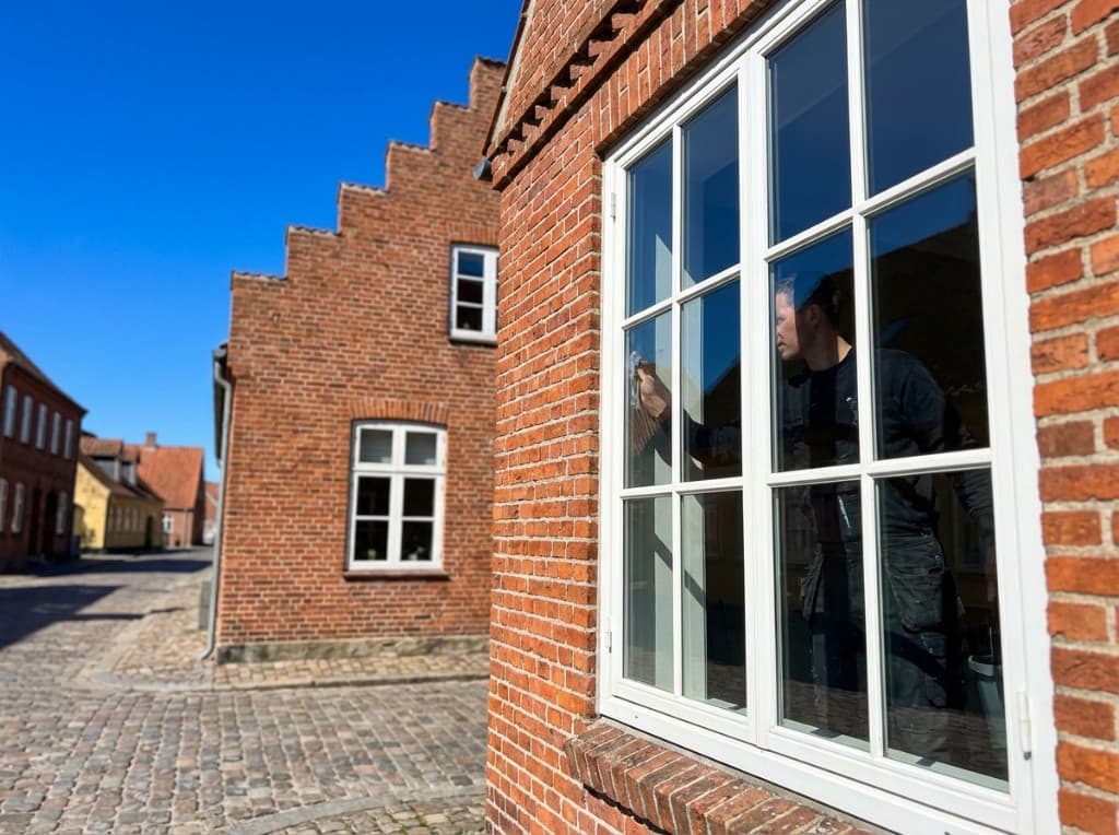 Hjælper pudser vindue i murstensfacade